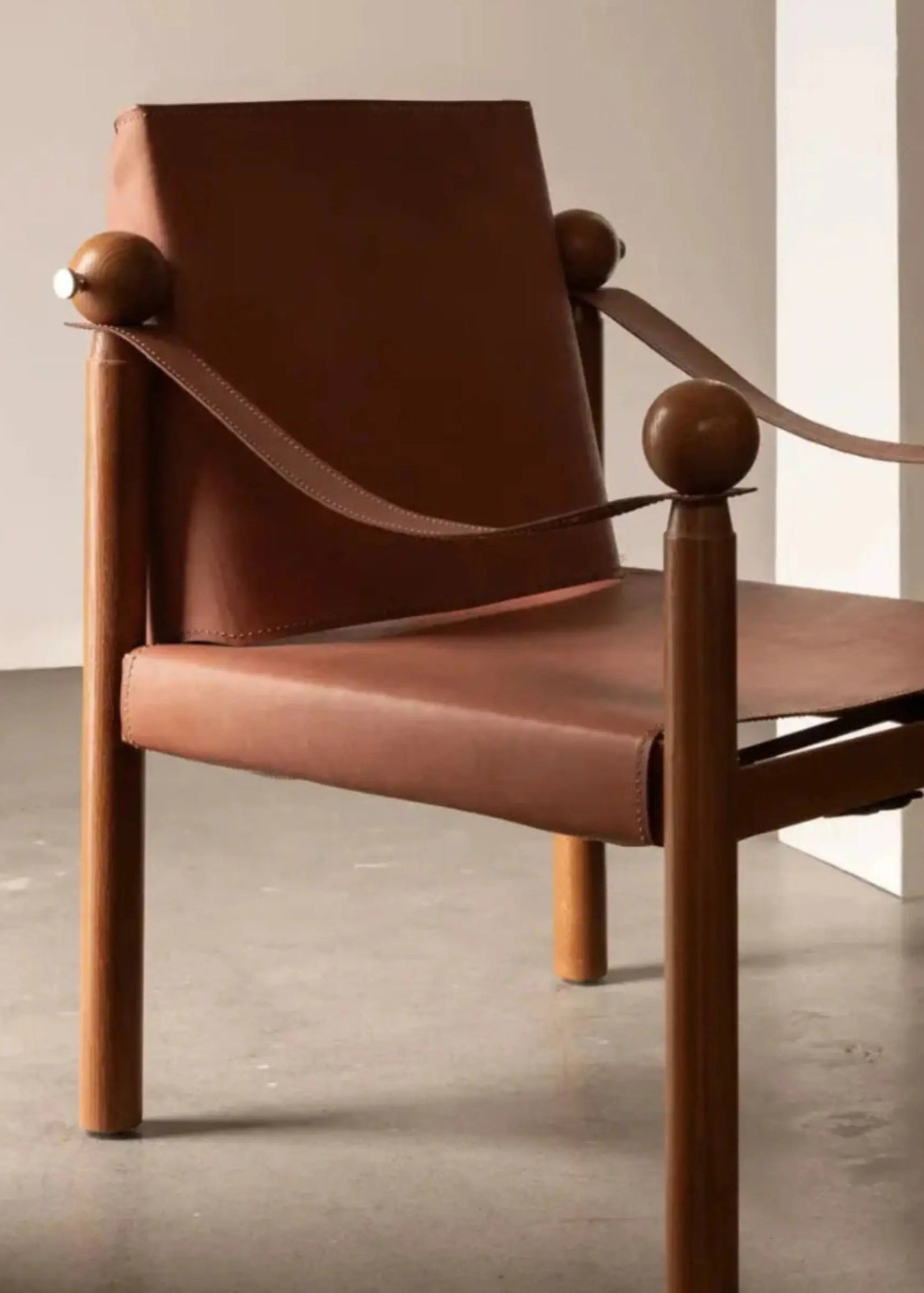 Brown leather chair with wooden armrests on a neutral background