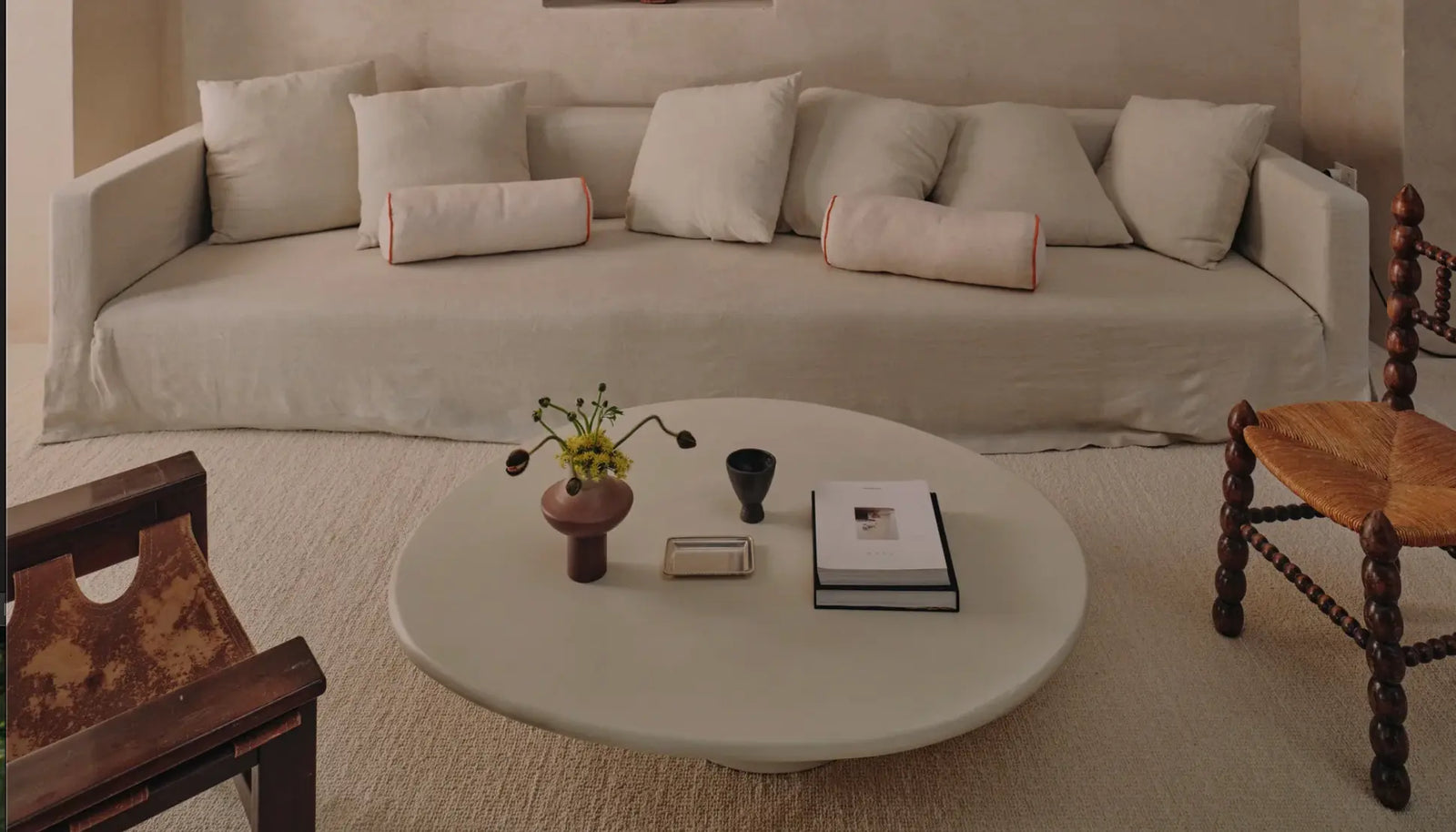 Living room with a beige sofa, round coffee table, and wooden chairs.